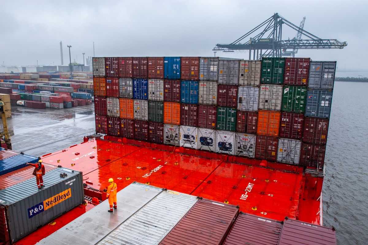 Dock workers and shipping containers on a cargo vessel at a port