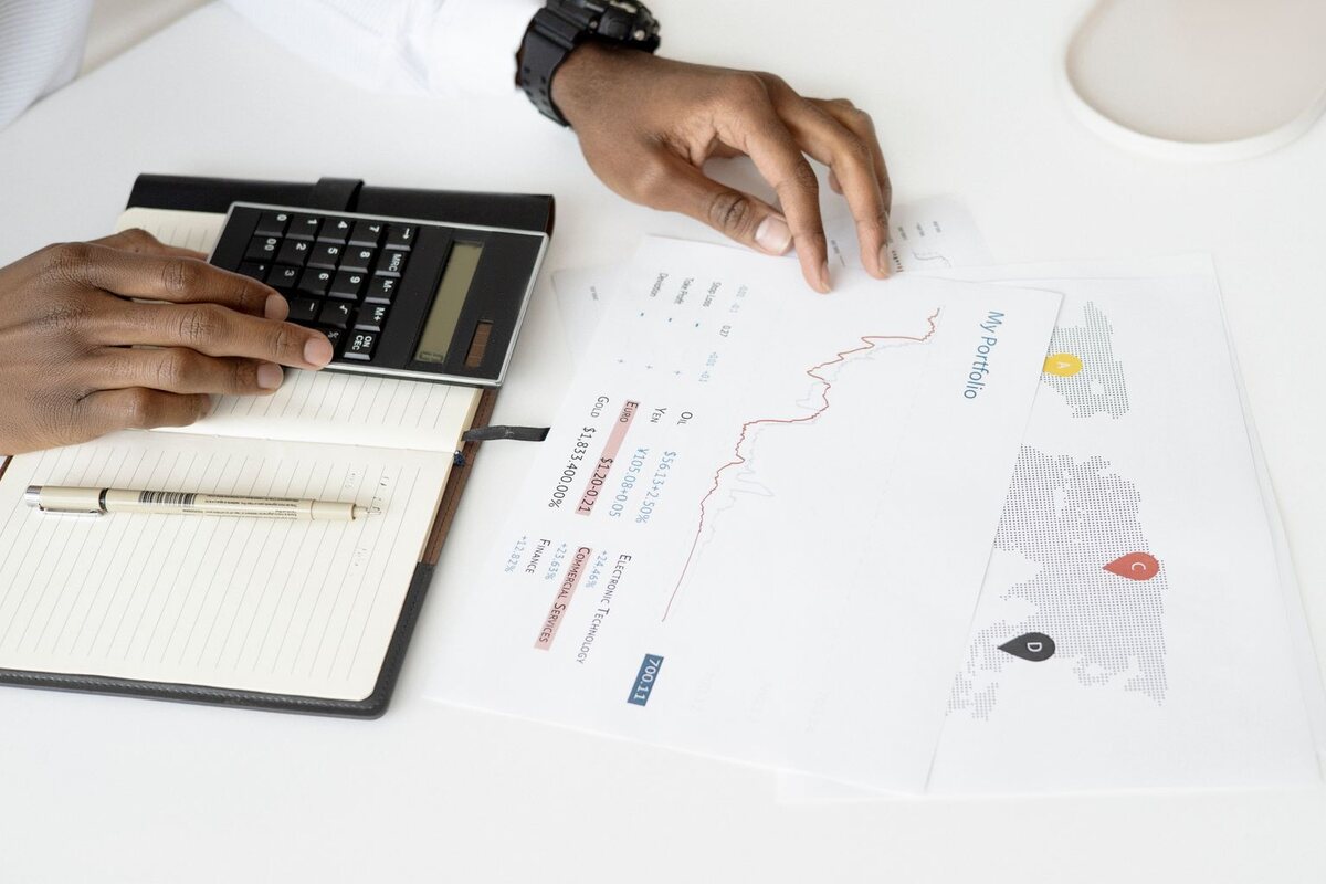 Buyer using a calculator to review printed business documents and figures at a bright office desk