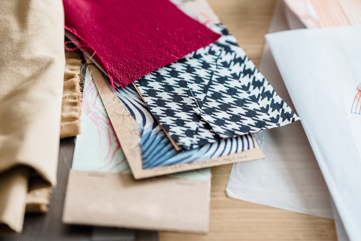 Fabric swatches and paper sketches arranged on a worktable for material comparison