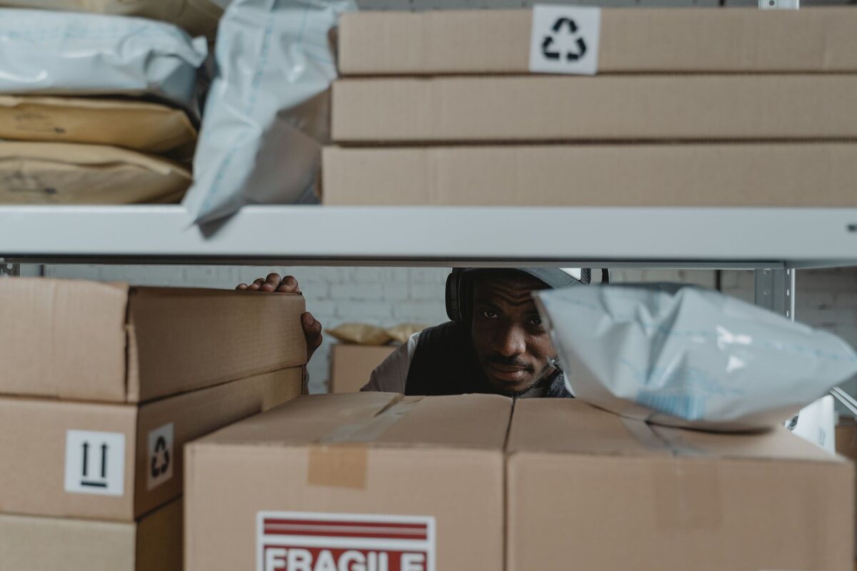 Warehouse worker checking labelled cartons and parcels on storage shelves during an inventory review